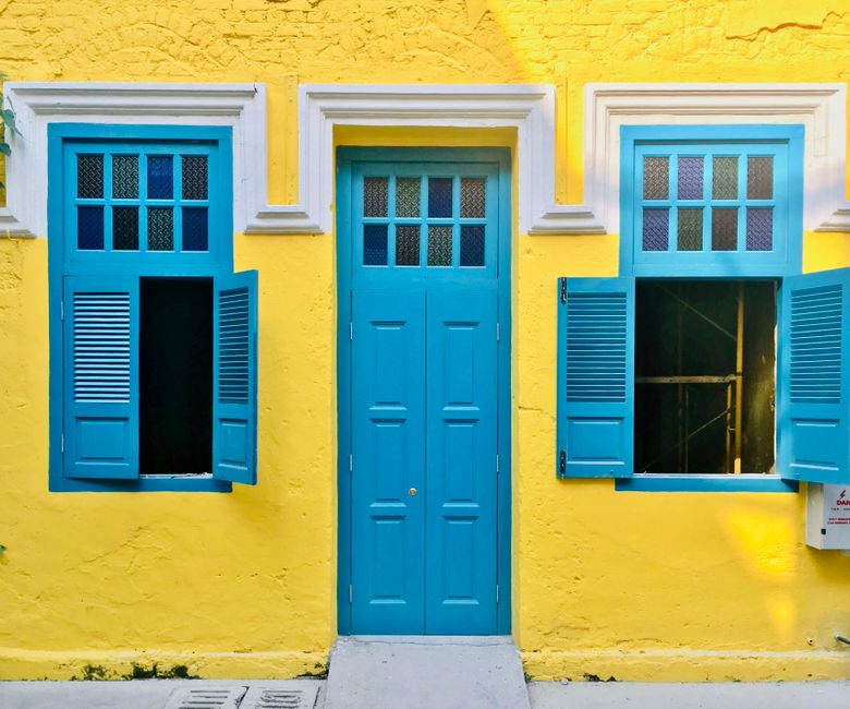 A painted wall with a blue door and windows