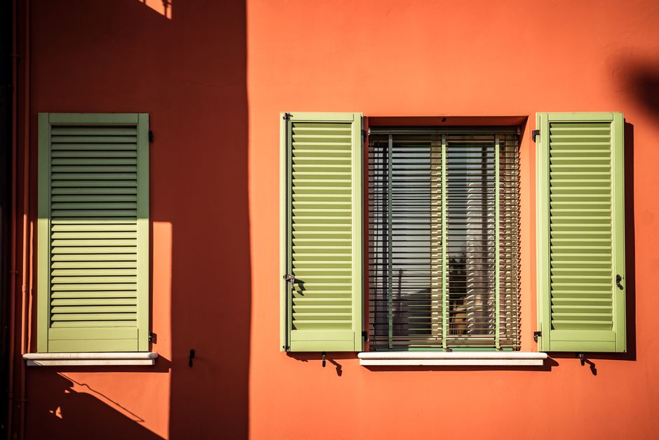 A freshly painted orange wall with green shutters