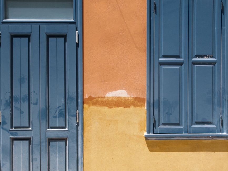An orange painted wall with a blue door and window