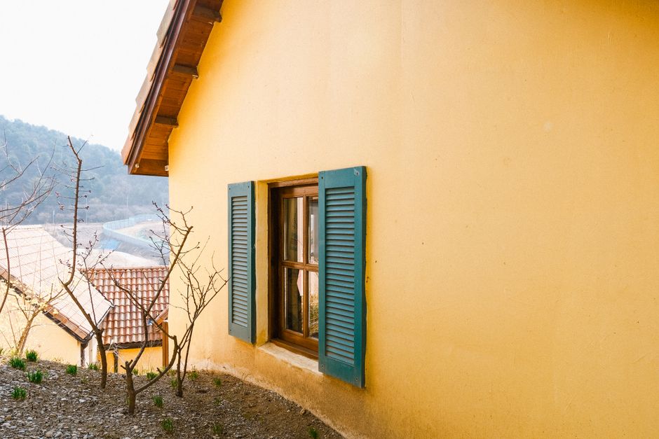 A yellow painted wall with blue shutters