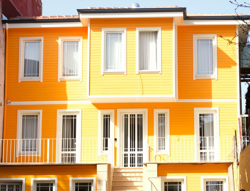 A yellow painted wall with white framed windows and door